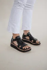 Sandalias negras de cuero con plataforma y tiras anchas.