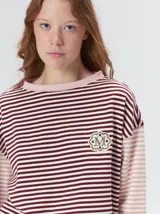 Remera de manga larga con diseño a rayas horizontales en tonos celestes y blancos en el cuerpo, y mangas a rayas azul marino y blancas. Presenta cuello redondo en color azul marino, logo bordado en el pecho y calce holgado.