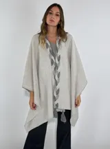 Ruana color beige con detalle de trenza en el frente y terminación con borlas.