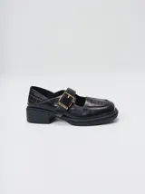 Zapatos tipo guillermina Mutma modelo Punko, color marrón, confeccionados en cuero. Presentan punta cuadrada, detalle texturizado en la parte delantera, tira en el empeine con hebilla metálica dorada y suela chunky de goma negra con taco bajo.