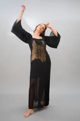 Vestido largo de gasa negra con estampado abstracto color dorado. Presenta mangas largas plisadas, escote cuadrado, tajo lateral y forro interior.