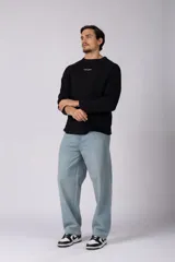 Buzo de cuello redondo y manga larga, confeccionado en tejido de punto acanalado de color negro. Presenta un diseño minimalista con un pequeño logo estampado en el pecho y un corte relajado.