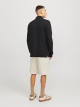 Short de corte relajado con tiro medio, confeccionado en tejido canvas de algodón y lino. Presenta cierre de cremallera, cordón ajustable en la cintura, bolsillos laterales y bolsillos traseros.