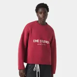 Suéter de punto grueso color bordó con diseño de cuello redondo y mangas largas. Presenta el logo de la marca Eme Studios tejido en técnica jacquard en el frente en color crema.