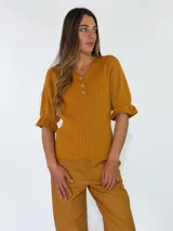 Top de tejido de punto color terracota, con escote en V, cuello camisero y cartera frontal con botones. Presenta mangas cortas con textura calada y puños con volados.