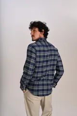 Camisa de manga larga confeccionada en tejido de franela con estampado de cuadros en tonos azul marino y verde. Presenta cuello abotonado, cierre frontal con botones y un bolsillo en el pecho con el logo bordado de la marca.