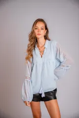 Camisa celeste de plumetí con cuello mao, mangas globo largas con puños elásticos y lazo en el escote.
