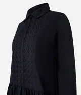 Vestido corto de corte evasé confeccionado en tricolina de algodón, color azul. Presenta cuello camisero, cierre frontal de botones y un panel central con detalle bordado calado. Posee mangas largas con puños abotonados.