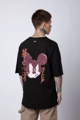 Remera negra de algodón de corte oversize, con mangas cortas y cuello redondo. Estampado pequeño en el frente y diseño grande en la espalda con Mickey Mouse y caracteres orientales en tonos rojizos.