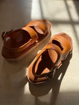 Sandalias de cuero metalizado color turquesa con diseño cut-out, tira en el empeine y suela plana con plataforma baja texturizada.