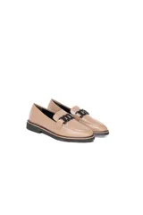Mocasín de cuero vacuno color visón, con diseño clásico de punta redondeada y costuras visibles. Presenta un adorno metálico negro en el empeine y suela plana de goma negra.