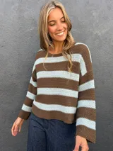 Sweater de punto a rayas horizontales en color marrón y celeste, con cuello redondo a la base y mangas largas.
