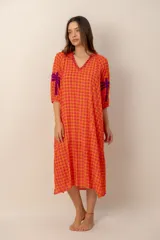 Vestido largo de corte holgado en tonos naranja y fucsia con estampado de cuadros vichy. Presenta cuello en V con detalles bordados, mangas tres cuartos y bordados decorativos de palmeras en contraste en las mangas.