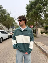 Buzo tipo polo de corte relajado y fit boxy, con diseño de bloques de color en bordó y blanco. Presenta cuello camisero con cierre frontal parcial y logo bordado en el pecho.