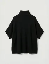 Capa tejida color fucsia, con cuello alto abotonado y mangas cortas estilo japonesa. Tejido de punto grueso.