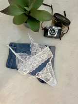 Conjunto de lencería compuesto por un top bralette y una tanga colaless, ambos confeccionados en encaje floral blanco con detalles de breteles regulables.
