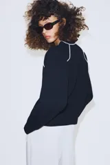Jersey de punto de manga larga con cuello redondo, diseño en color azul marino con detalles de vivo en color blanco en el cuello y las costuras de las mangas.