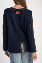 Sweater de tejido de punto con calce oversize, color azul marino con detalles en color marrón en las mangas y cuello. Presenta un diseño de manga larga y puños y ruedo acanalados.