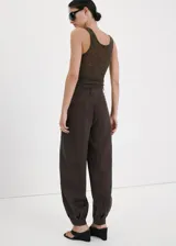 Pantalón balloon de tiro medio color marrón oscuro, con diseño de pinzas, trabillas y bolsillos laterales. Cuenta con cierre de gancho y cremallera.