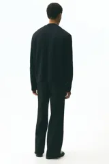 Cárdigan negro de punto fino con textura cepillada y cuello en V pronunciado. Presenta botonadura frontal y corte estándar.