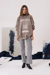 Buzo de calce oversized color gris con efecto desgastado, cuello redondo, mangas largas y estampa frontal con diseño cinematográfico.