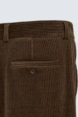 Pantalón de corte wide fit confeccionado en pana de algodón color marrón oscuro. Presenta bolsillos frontales, bolsillos traseros de vivo con botón y cierre frontal con cremallera y botón.