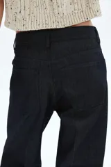 Jean de cinco bolsillos en denim de algodón color azul oscuro, de tiro medio y pierna recta muy ancha. Presenta pliegues cosidos marcados en el frente de cada pierna.