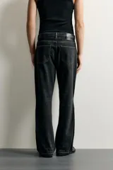 Jeans flare fit de denim negro, tiro medio, ajustados arriba y con botamanga acampanada. Cuentan con cinco bolsillos, lavado efecto gastado y bajo con acabado irregular. Cierre frontal con cremallera y botón.