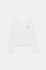 Remera blanca de manga larga y cuello redondo con detalle de texto impreso en el pecho en color azul.