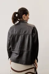 Camisa de cuero color negro, de manga larga con puños abotonados, cierre frontal con broches metálicos y un bolsillo aplicado en el pecho.