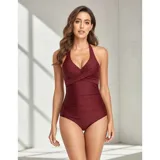 Malla entera de color verde oscuro, combinada con un diseño floreado en la parte inferior. Presenta escote halter cruzado y fruncidos en la zona del abdomen.