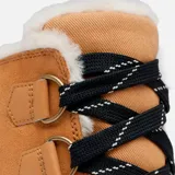 Bota de invierno Sorel modelo Tivoli V, confeccionada en gamuza impermeable color curry con refuerzos de goma negra en la base y el talón. Presenta interior forrado en piel sintética, cierre con cordones y suela de goma dentada color marrón.