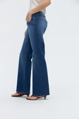 Jean de denim azul con calce recto y pierna amplia de caída relajada, tiro bajo y bolsillos clásicos.