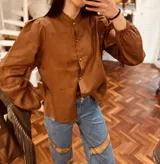 Camisa marrón de lino con cuello mao, mangas largas abullonadas con puños elásticos y cierre frontal con botones.