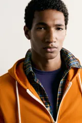 Sudadera con capucha y cierre frontal de cremallera, de corte relaxed fit, confeccionada en tejido de algodón con estructura waffle en color naranja. Cuenta con bolsillos frontales de vivo, cordones ajustables blancos y acabados en rib.
