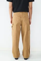 Pantalón estilo carpintero de corte holgado, color camel, con bolsillos laterales funcionales y cierre frontal de botón.