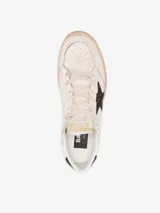 Zapatillas deportivas de cuero color blanco con detalles en negro y estrella de glitter color borgoña.