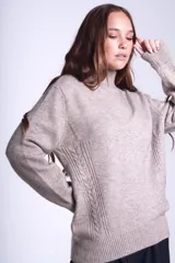 Sweater color beige de tejido de punto con cuello alto y mangas largas. Presenta detalles de ochos en diagonal en los laterales.