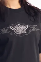 Remera de corte holgado color negro, con estampa frontal de una mariposa con detalles tribales y llamas en tonos grises.