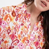 Vestido corto con cuello mao, mangas 3/4 y falda con volados. Estampado con motivos geométricos en tonos naranja, rosa y blanco. Incluye cinturón fino del mismo tejido.