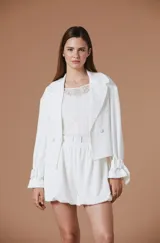 Saco corto de corte sastrero en color bordó, con solapas clásicas, cierre frontal de doble botonadura y mangas largas con detalle de lazos ajustables en los puños.