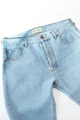 Jean de corte recto clásico con cinco bolsillos, botones de cobre y costuras color camel.