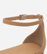 Sandalia plana color nude con tira fina con aplicación de strass y mini espejos, cierre en el tobillo, puntera redonda y taco bajo plano.