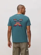 Remera de algodón orgánico color verde azulado, con corte regular fit y el logo de la marca en forma de X bordado en la espalda con diseño de rayas multicolores.