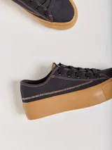 Championes de lona negra con plataforma y puntera de goma marrón, cordones negros y costuras en contraste.