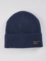 Gorro de lana tejido en punto canalé, color azul marino, con vuelta en el borde y etiqueta decorativa de la marca Benson & Thomas.