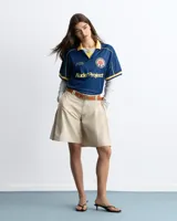 Remera de fútbol estilo vintage de la marca Nude Project, en color azul marino con cuello polo y detalles en amarillo. Presenta inscripciones y un escudo bordado en el pecho.