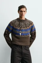 Jersey de punto con diseño jacquard geométrico en la parte superior, cuello redondo y manga larga. Presenta un corte relajado con acabados en rib en puños y ruedo.