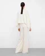 Top satinado blanco estilo capa de línea rectangular, con escote redondo, pliegue en la espalda y cierre de botón con lágrima.