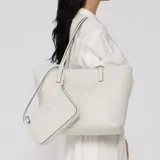 Cartera tipo tote bag Guess modelo Keira, color blanco, confeccionada en PVC con textura saffiano. Cuenta con un gran parche triangular con el logotipo de la marca en relieve en el frente, doble asa superior y viene acompañada de un pequeño bolso tipo pochette con cierre y correa corta desmontable.